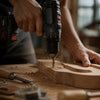 Person using a cordless drill on a piece of wood with tools around