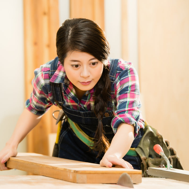 Woman working with wood at a table in a workshop setting